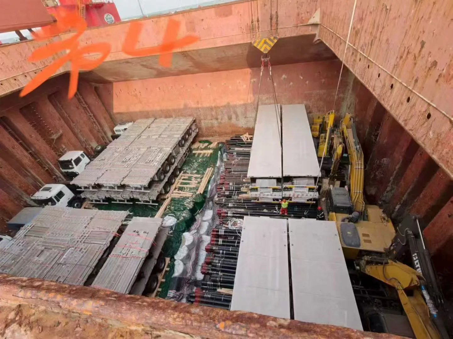 Overhead view of a break bulk vessel cargo hold loaded with excavators, trailers, and mixed heavy cargo